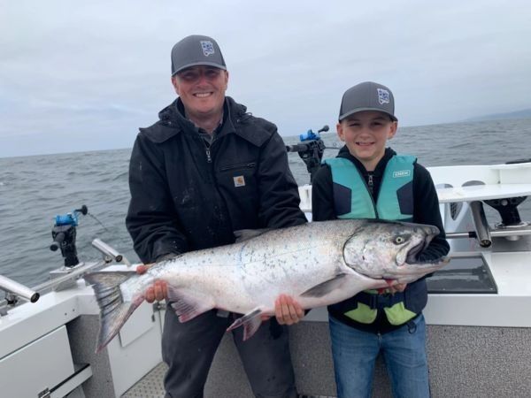 A father and son holding a big king salmon aboard Fish Invader
