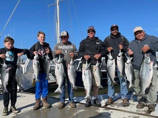 A family group with kids lined up with their salmon catch